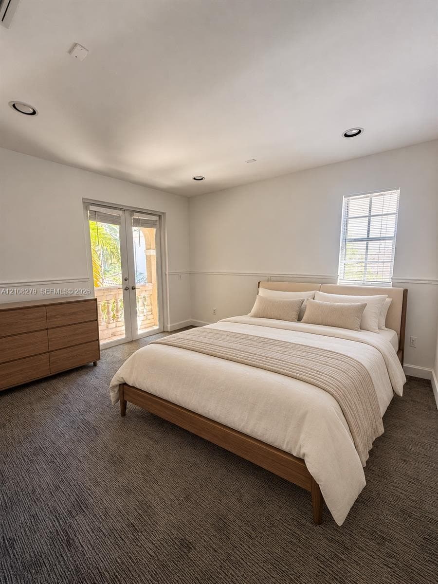 Bedroom interior featuring neutral wall-to-wall carpeting, recessed ceiling lighting, chair rail molding, a double-hung window, and glass-paneled french doors