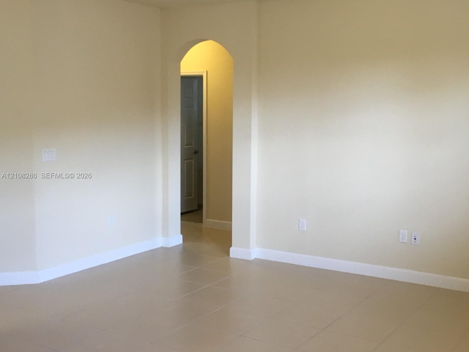 Neutral walls with arched doorway featuring classic architectural detailing and neutral-toned tile flooring
