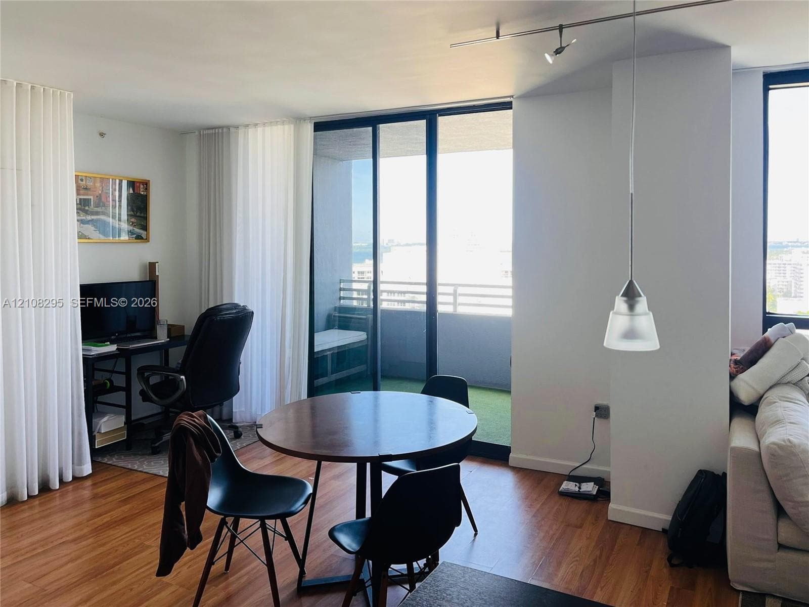 Living space featuring wood-finish flooring, floor-to-ceiling sliding glass doors, a private balcony, pendant lighting, and track lighting