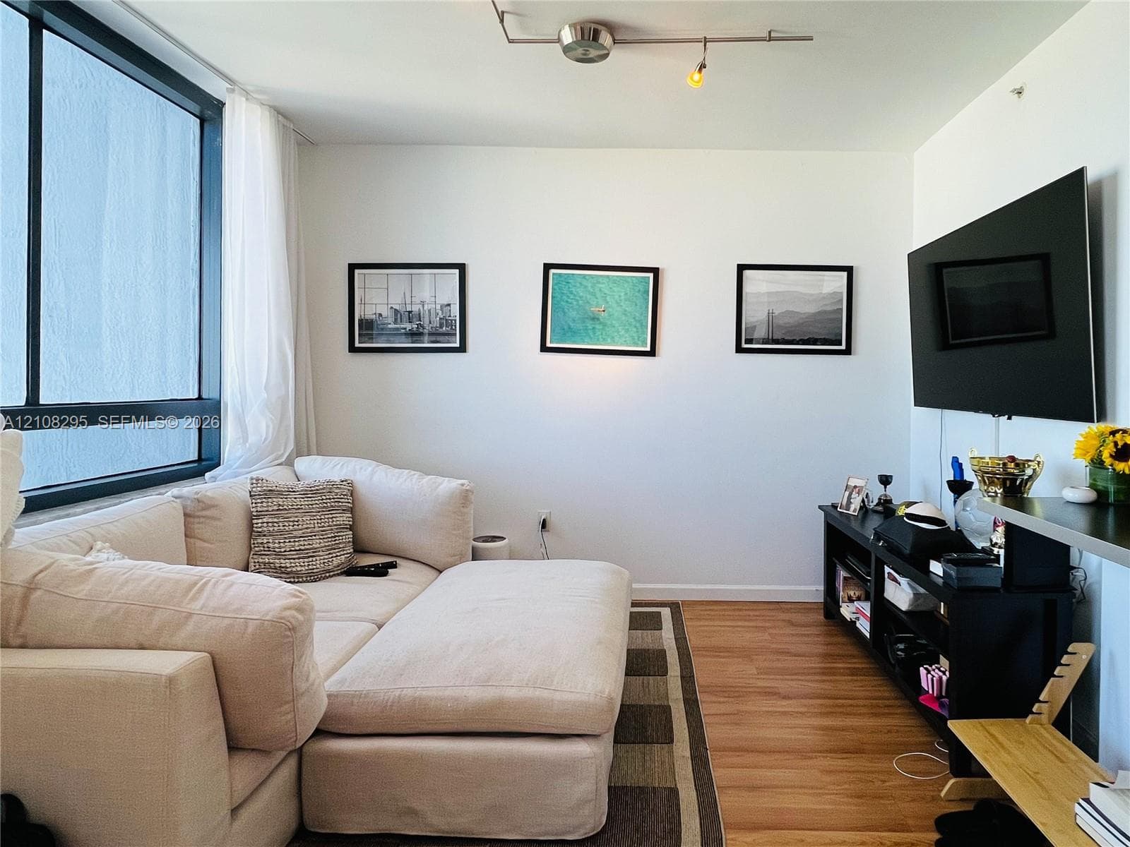 Floor-to-ceiling windows, wood-finish flooring, and adjustable rail lighting
