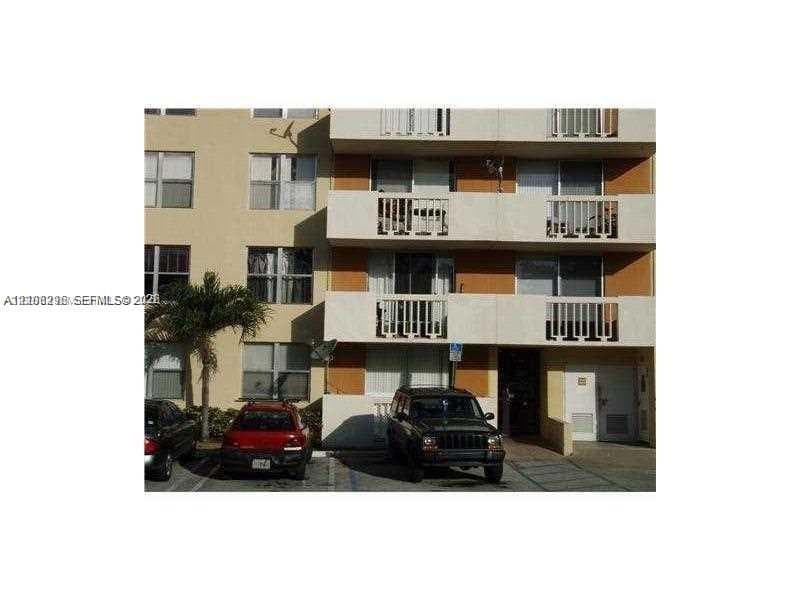 Multi-story exterior facade featuring concrete balconies with vertical railings, stucco finish, grid-pattern windows, and exterior parking