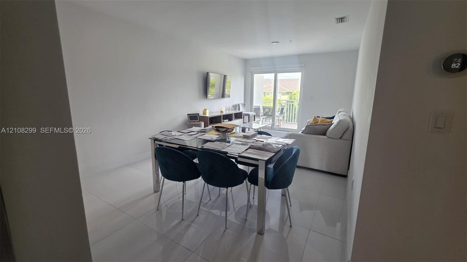 Open-concept interior featuring large-format tile flooring, neutral wall tones, and glass sliding doors providing exterior access