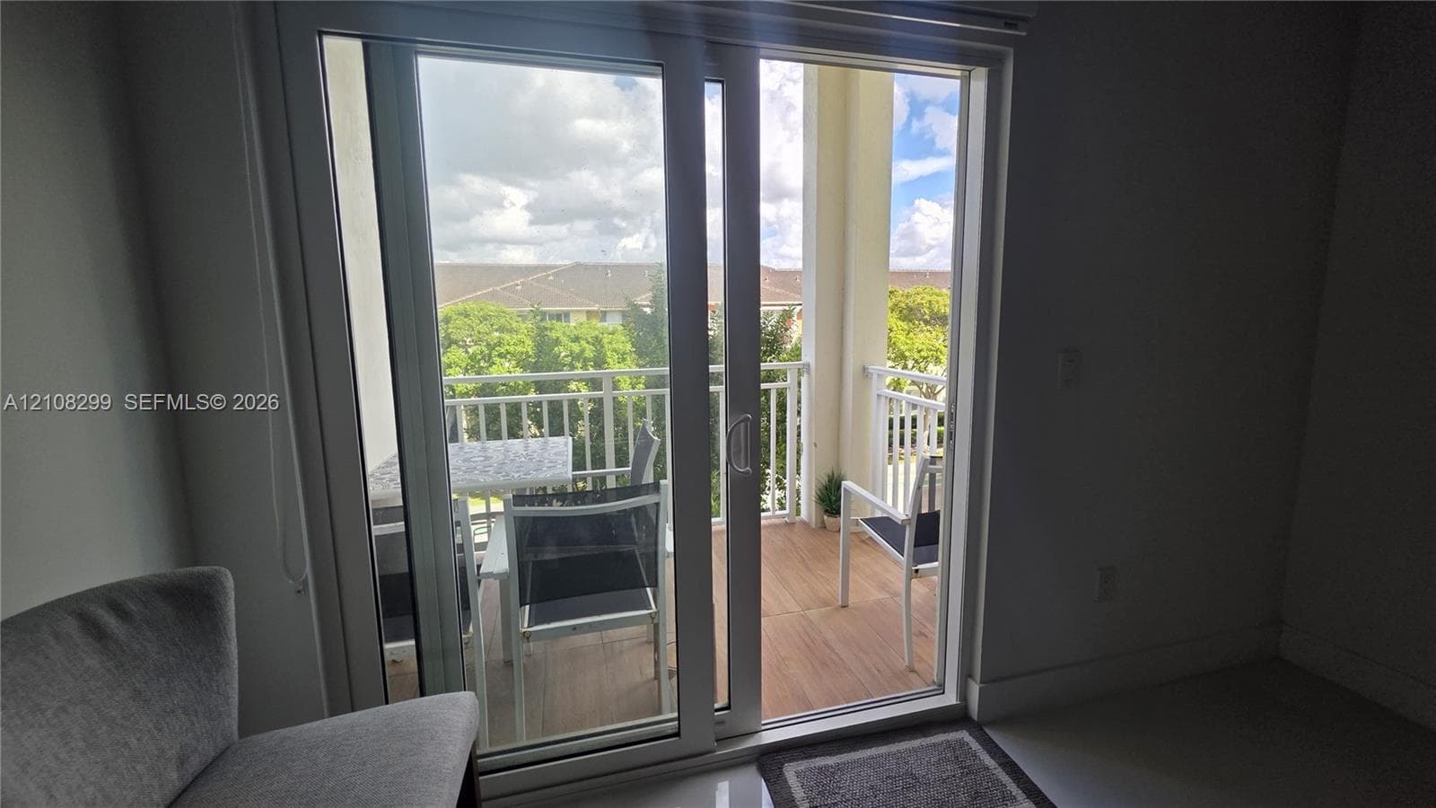 Glass sliding door opening to a private balcony with wood-finish decking and white metal railings