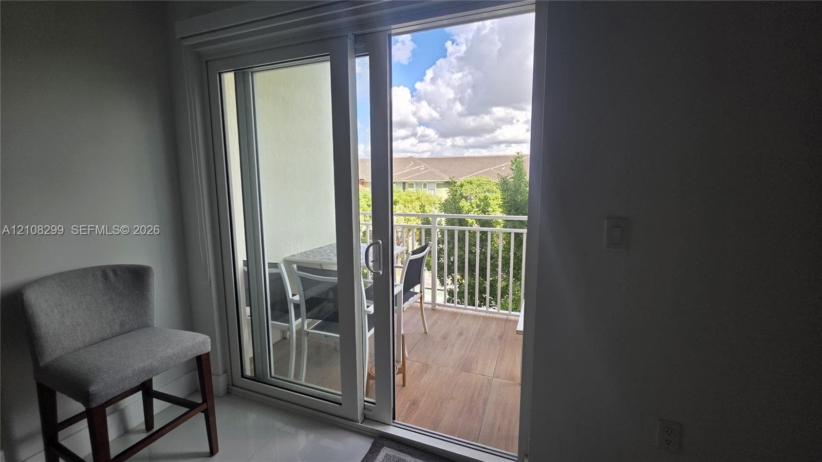 Sliding glass door opening to a private balcony featuring white metal railings and wood-finish flooring