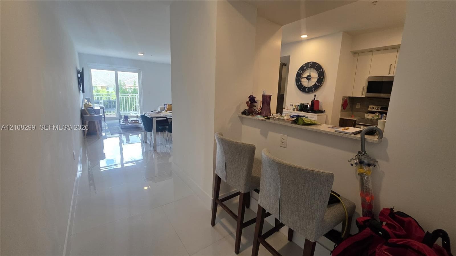 Kitchen featuring white cabinetry, built-in stainless steel appliances, and a pass-through breakfast bar finished with a neutral countertop, complemented by polished tile flooring throughout