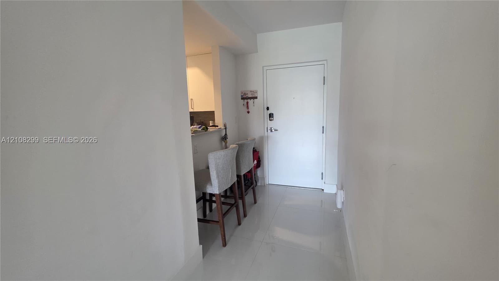 Entryway featuring large-format tile flooring, a solid core door, and a pass-through counter