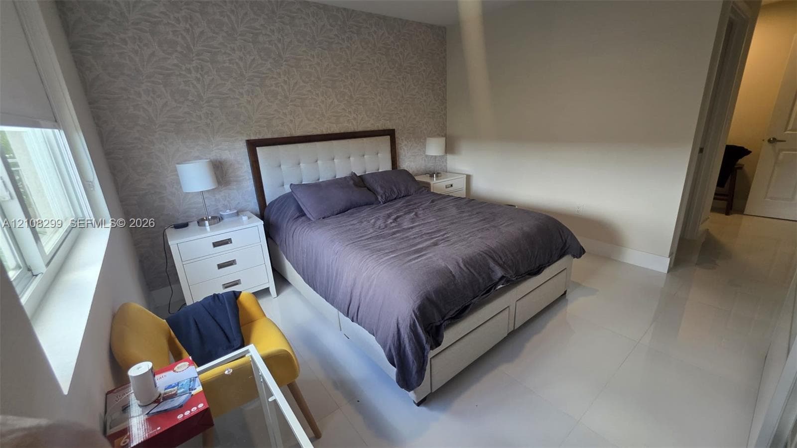Room featuring large-format tile flooring, a patterned accent wall, and a multi-pane window