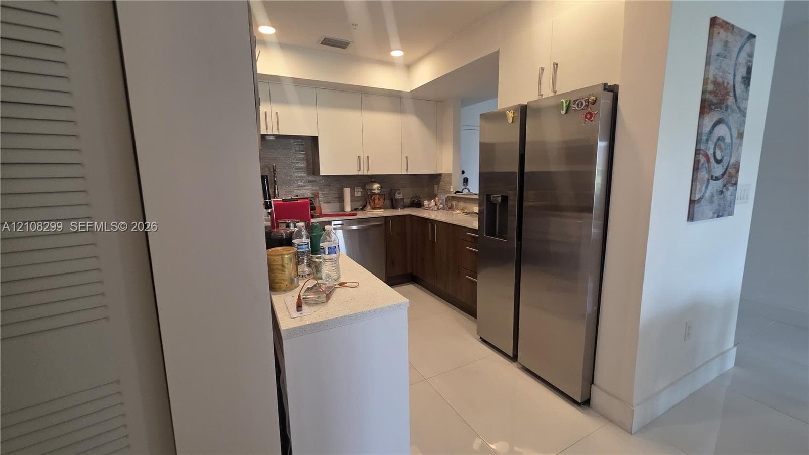 Kitchen featuring flat-panel two-tone cabinetry, quartz countertops, stainless steel appliances, and large-format tile flooring