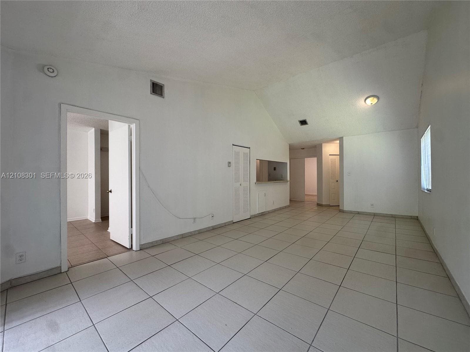 Vaulted ceilings, large-format tile flooring, and interior pass-through window with counter ledge