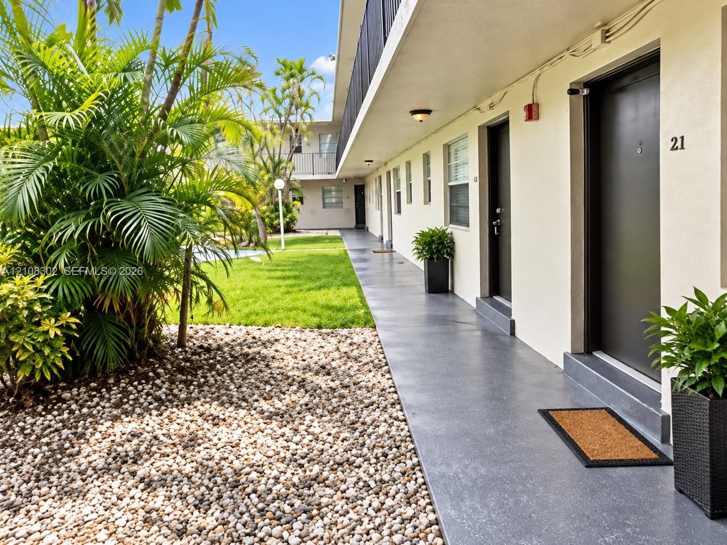 Exterior walkway featuring a concrete surface, overhead flush-mount lighting, and access to units