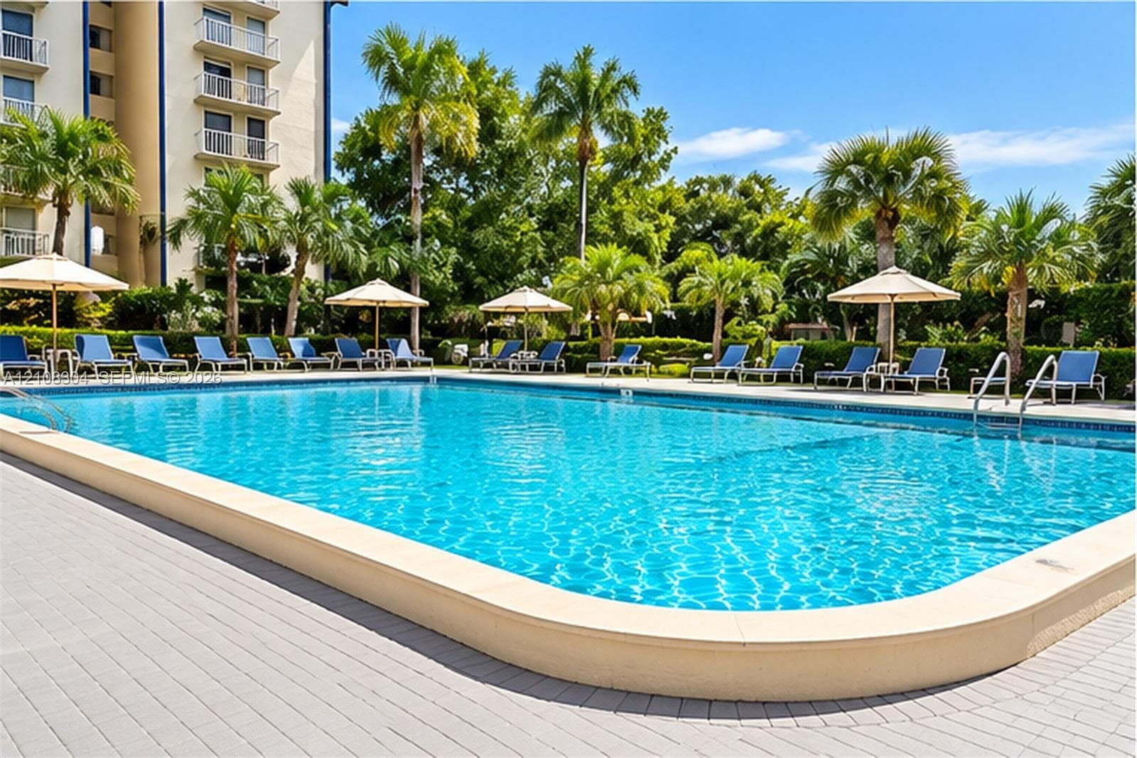 Swimming pool with a stone paver deck, palm tree landscaping, and metal pool entry rails