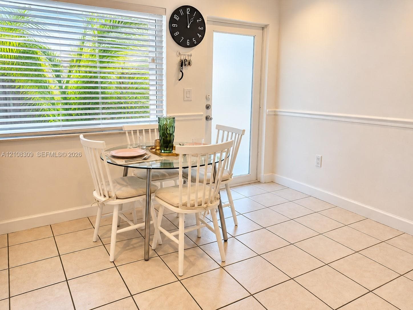 Ceramic tile flooring, white chair rail molding, large horizontal blind window, and glass-paneled exterior door