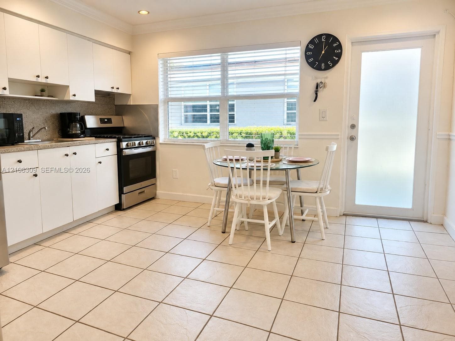 Kitchen featuring white flat-panel cabinetry, stone-finish countertops, stainless steel gas range, tile flooring, and a glass-paneled exterior door