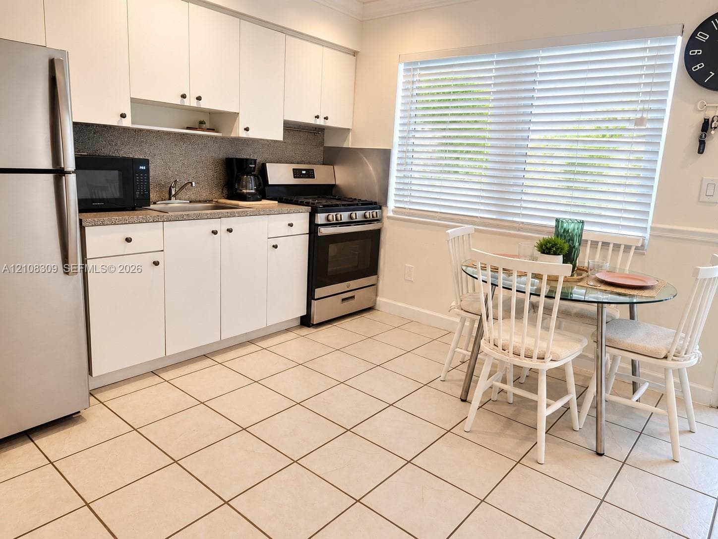 Kitchen featuring white cabinetry, stone-finish countertops, stainless steel appliances, and tile flooring