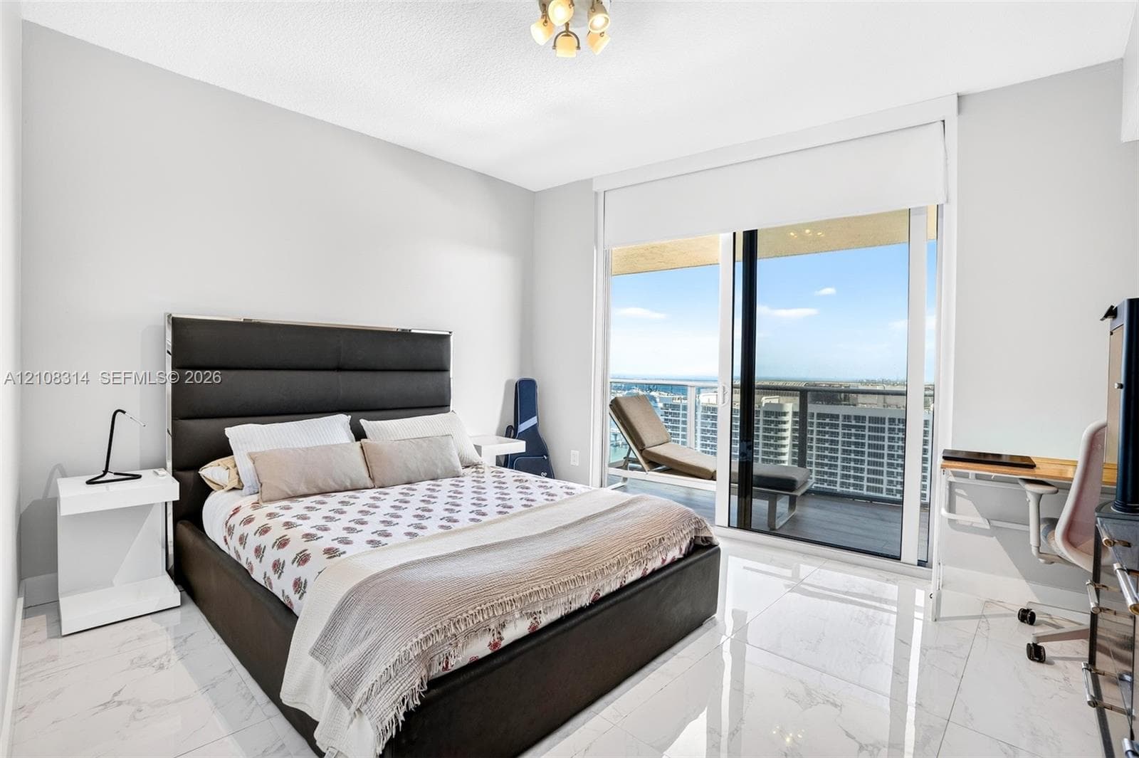 Floor-to-ceiling sliding glass doors, white large-format stone-finish flooring, and recessed ceiling lighting