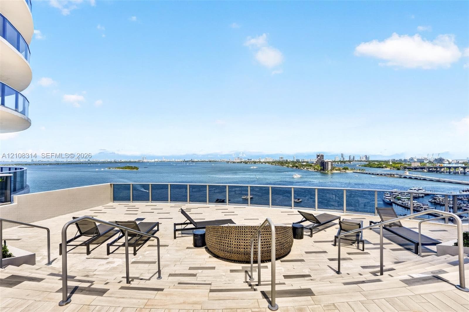 Expansive rooftop terrace featuring patterned stone-finish flooring, metal railing, and multi-level stepped access