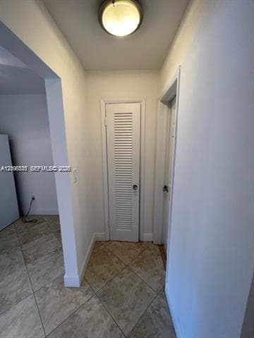 Neutral-toned ceramic tile flooring laid in a diagonal pattern, white interior doors, and a flush-mount circular ceiling fixture