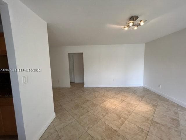 Neutral-toned interior space featuring diagonal tile flooring, smooth wall finishes, and a four-bulb ceiling-mounted light fixture
