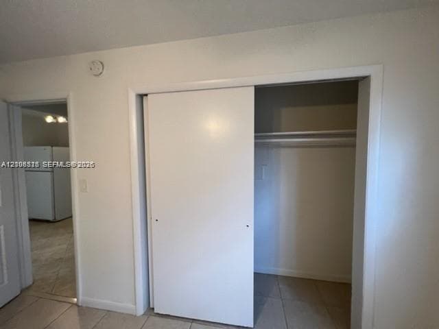 Closet featuring sliding doors and built-in shelving, complemented by tile flooring