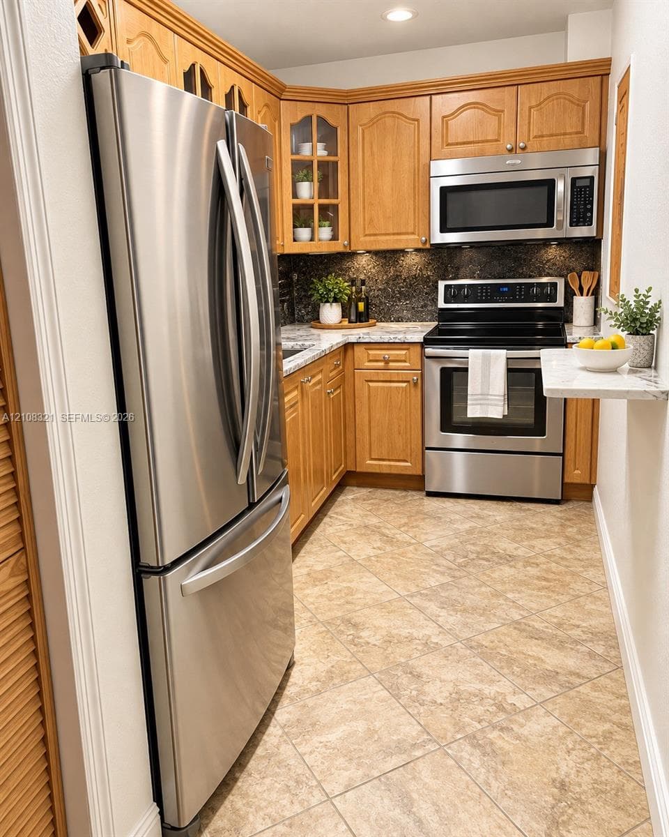 Kitchen featuring natural wood cabinetry with glass-panel upper accents, stone-surface countertops, tile flooring, and stainless steel appliances including a French-door refrigerator and built-in microwave