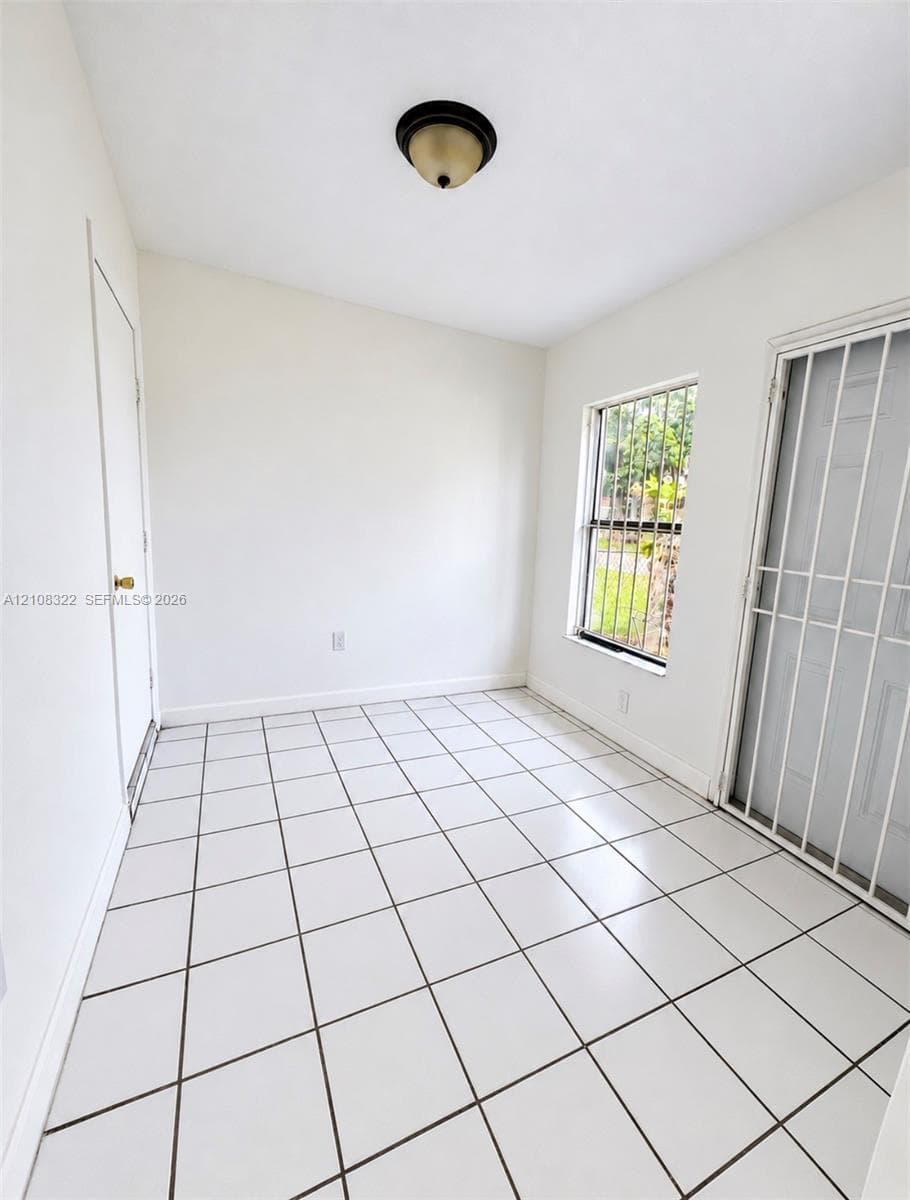 Interior space featuring white tile flooring, flush-mount ceiling lighting, and a metal security door