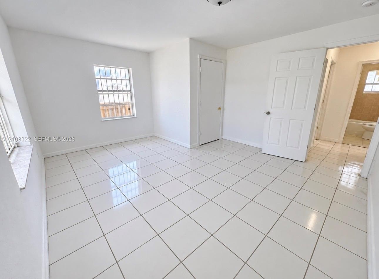 Neutral-toned interior space featuring polished tile flooring, white-painted walls, and six-panel interior doors