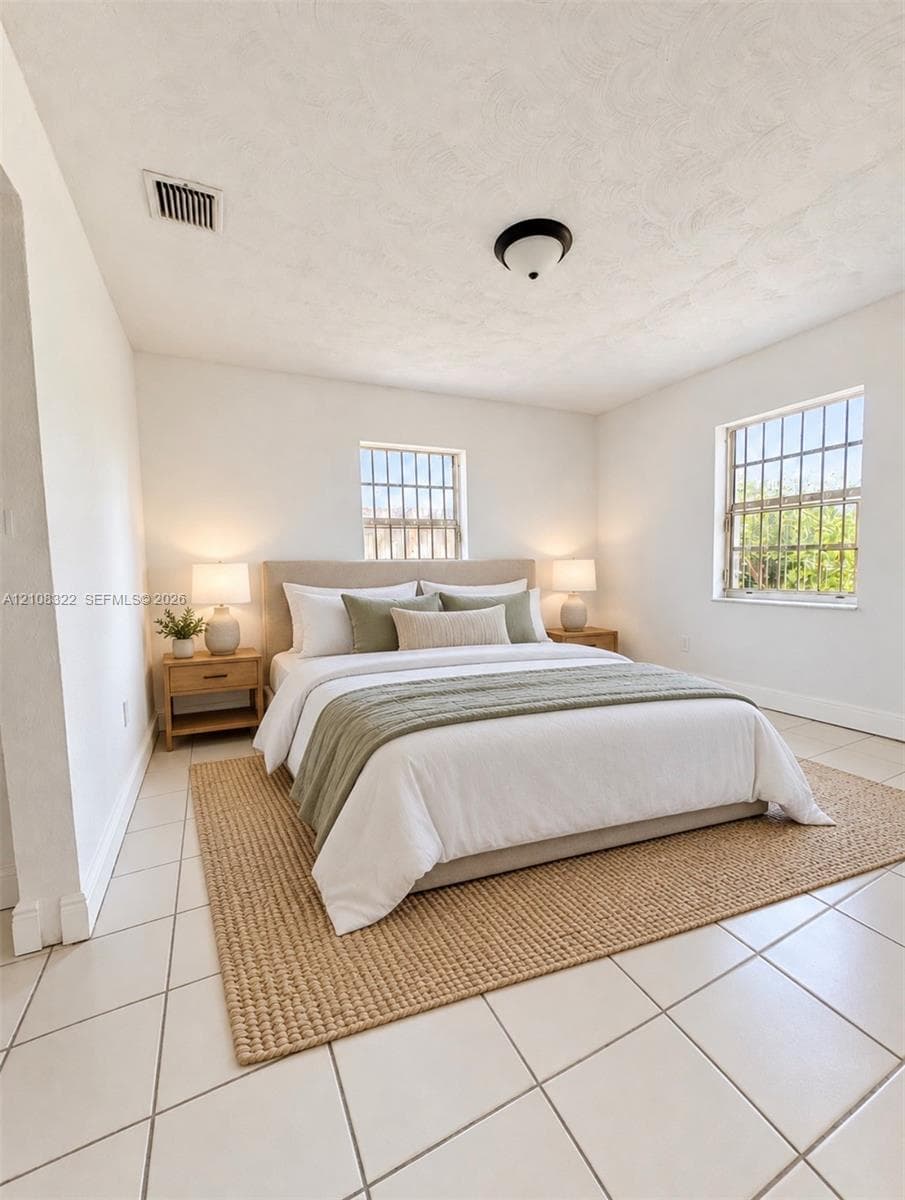 Interior space featuring neutral wall tones, large-format ceramic tile flooring, and dual windows with security bars