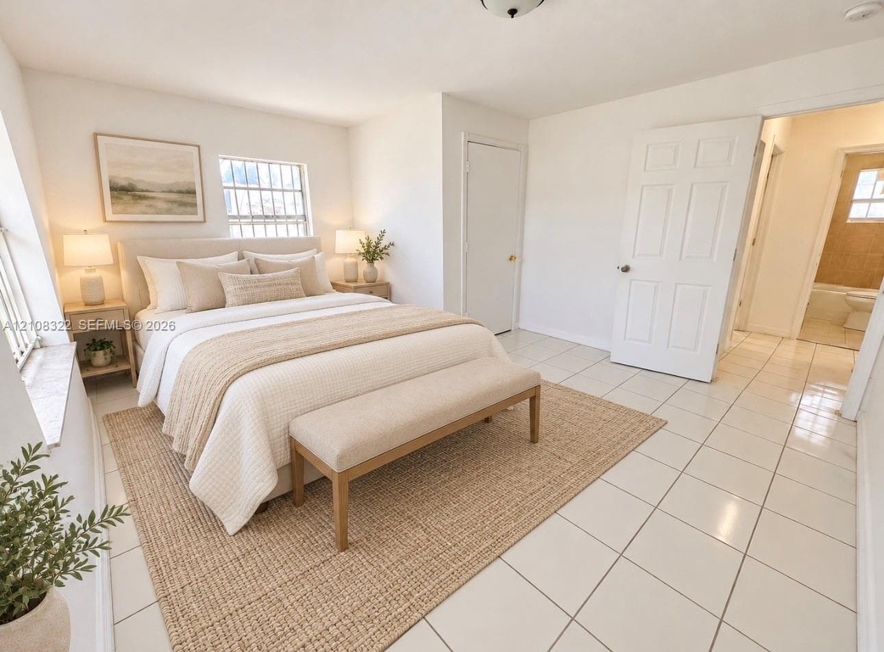 Neutral-toned interior space featuring light-colored ceramic tile flooring, multiple windows providing natural light, and a six-panel interior door