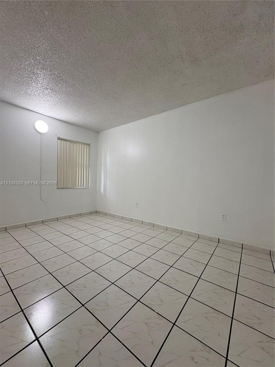Interior space featuring neutral wall paint, square ceramic floor tiles, and a window with vertical blinds