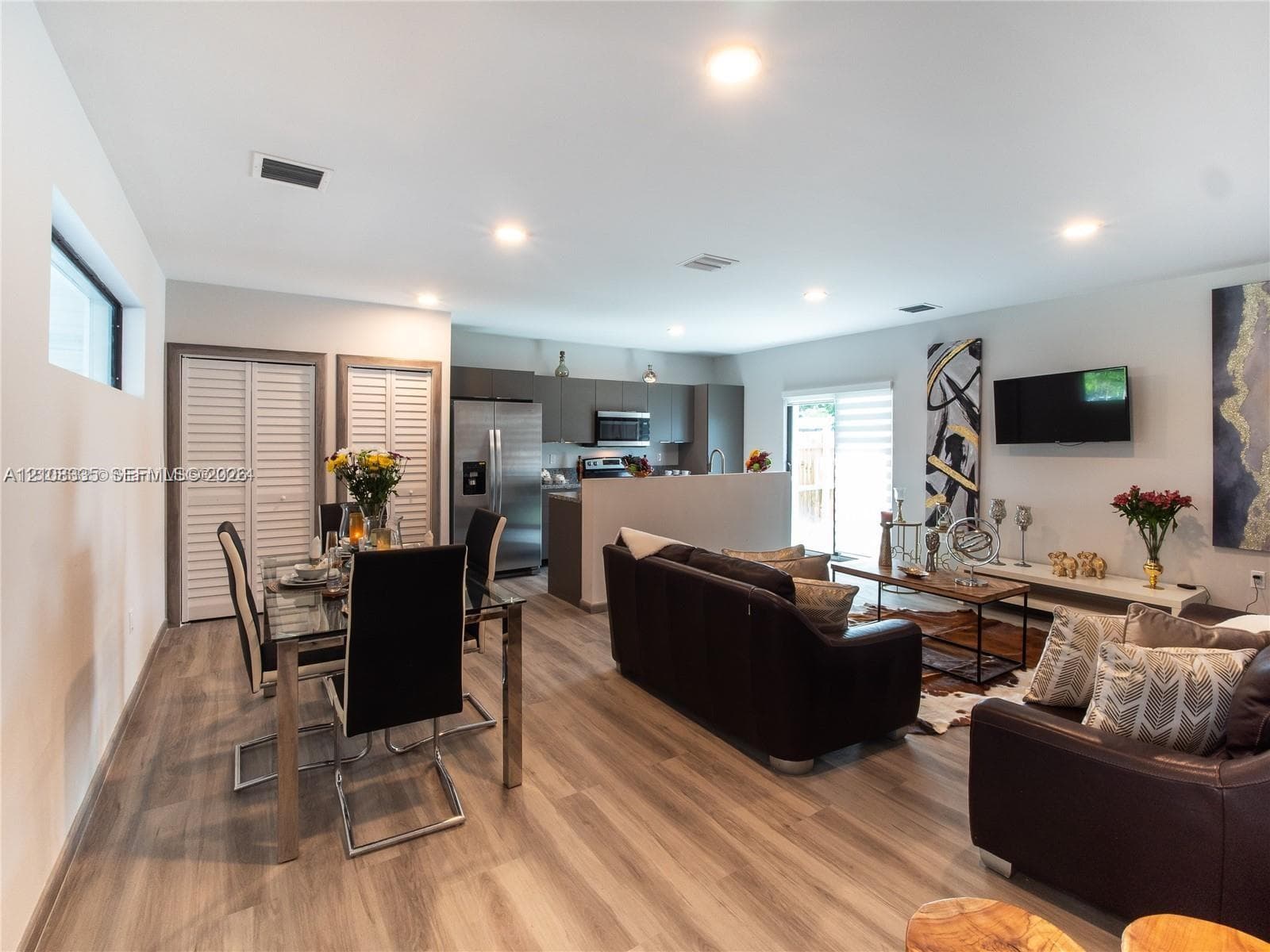 Open-concept interior featuring wood-finish flooring, recessed lighting, neutral wall tones, and floor-to-ceiling louvered closet doors