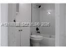 Bathroom featuring a vanity with integrated storage, solid-surface tub surround, and wall-mounted shower fixture