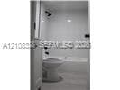Bathroom featuring a white bathtub and shower surround, wall-mounted shower head, matte black fixtures, and a white toilet
