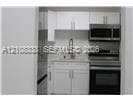 Kitchenette featuring white cabinetry, stainless steel appliances, a built-in microwave, and a gooseneck faucet