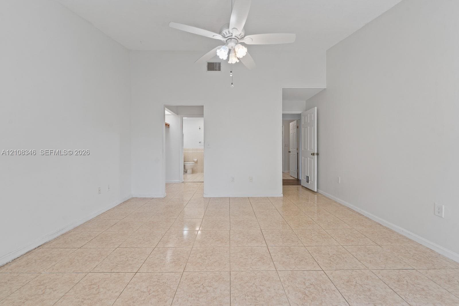 Room featuring tile flooring, vaulted ceilings, and a ceiling-mounted light fixture with fan