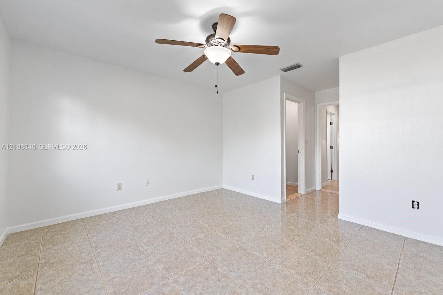 Neutral-toned tile flooring, white wall finish, and a ceiling-mounted fan with integrated light fixture