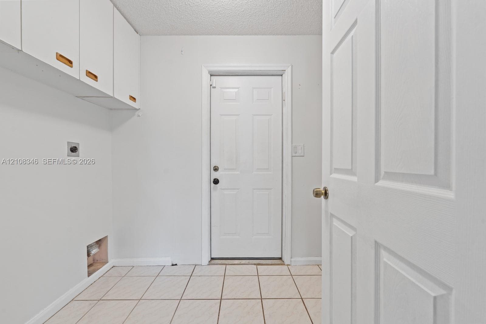 Neutral-toned square tile flooring, light-filled interior with single-pane window, and ceiling-mounted fan with integrated light fixture