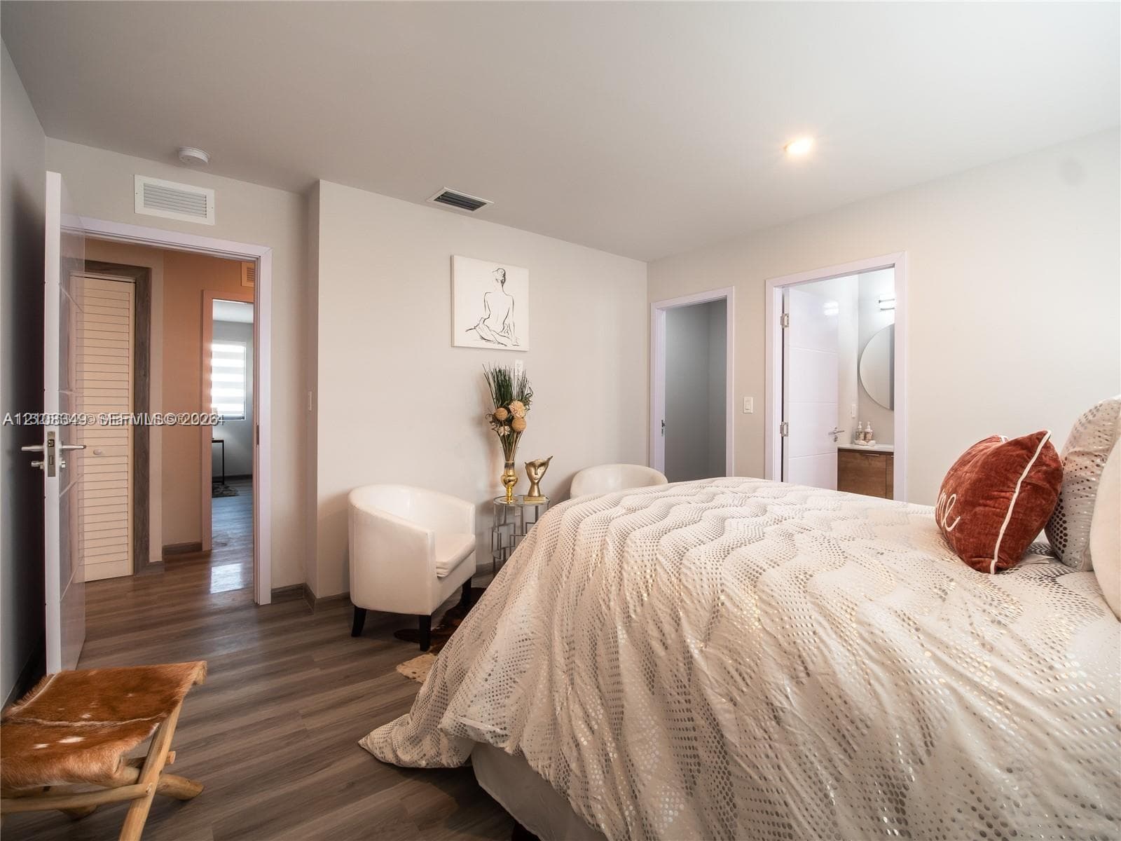 Room featuring wood-finish flooring, neutral wall paint, and double-entry doors including a louvered closet door
