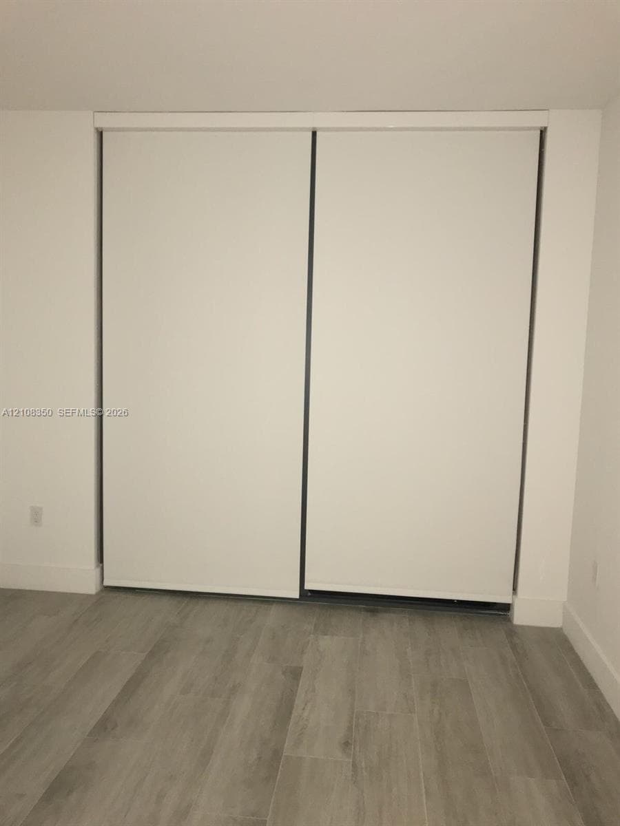 Sliding closet with white panel doors and wood-finish flooring