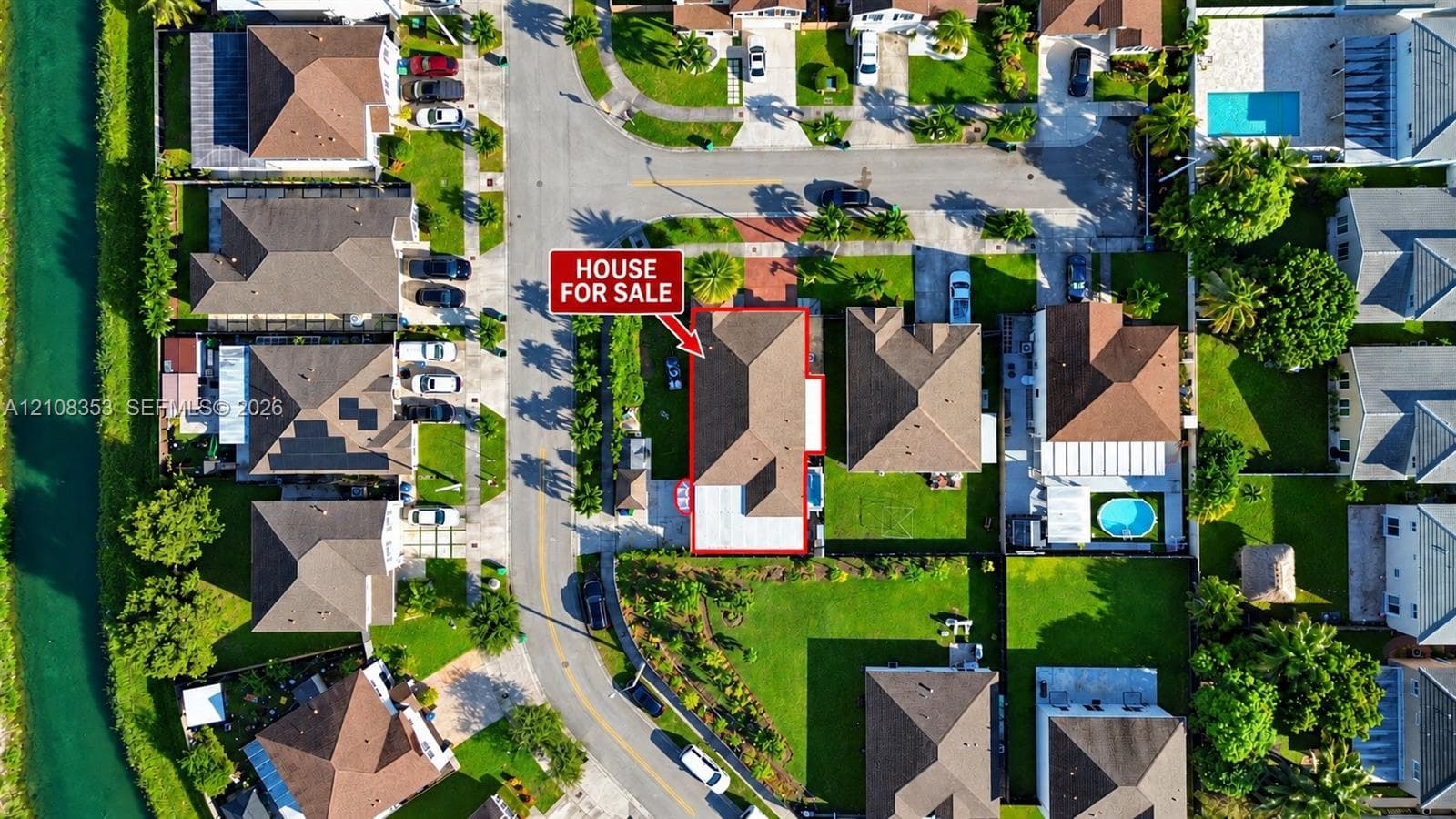 Aerial perspective featuring a multi-hipped roofline, paved driveway, and established landscape elements