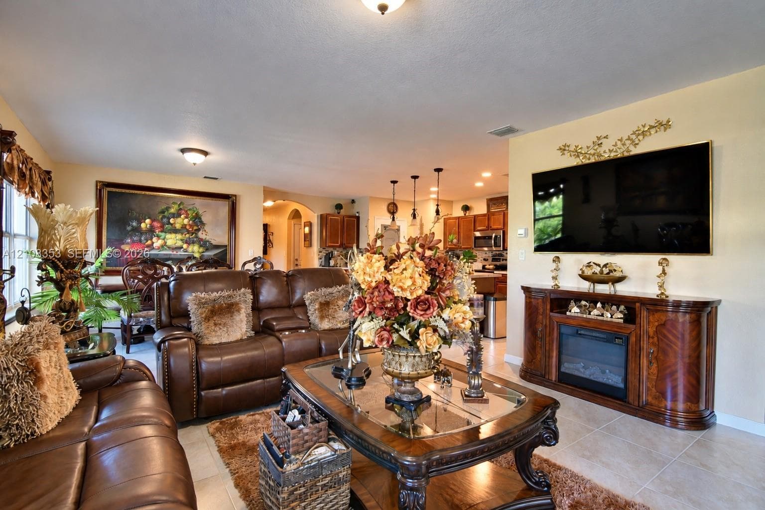 Neutral-toned interior featuring ceramic tile flooring, recessed ceiling lighting, arched room entries, and an integrated wall-mounted electric fireplace console