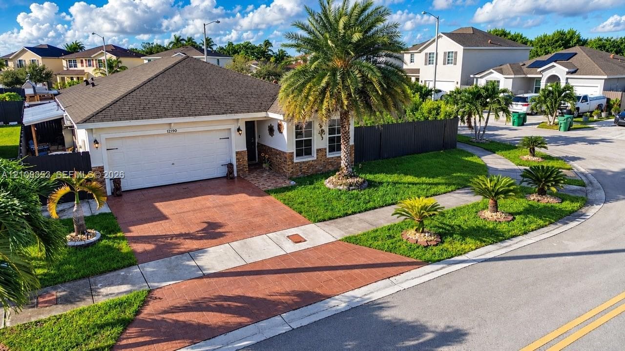 Single-story residence featuring a hipped roof, attached two-car garage, stone-veneer facade accents, and a paved driveway