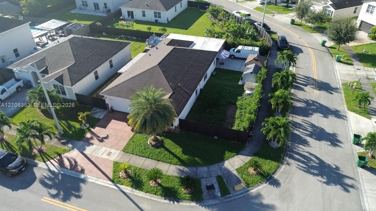Corner lot residence featuring a paver driveway, dark-tone roof shingles, and a fenced backyard