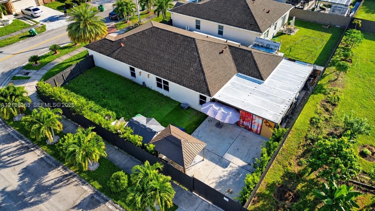 Single-story residence featuring a dark shingle roof, concrete patio, detached metal gazebo, and perimeter privacy fencing