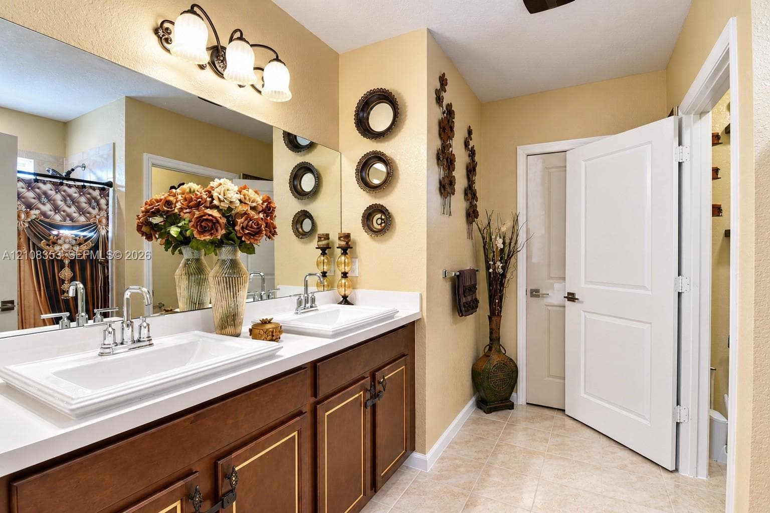 Double vanity featuring rectangular drop-in sinks, polished chrome faucets, a solid-surface countertop, and dark wood cabinetry with trim detailing