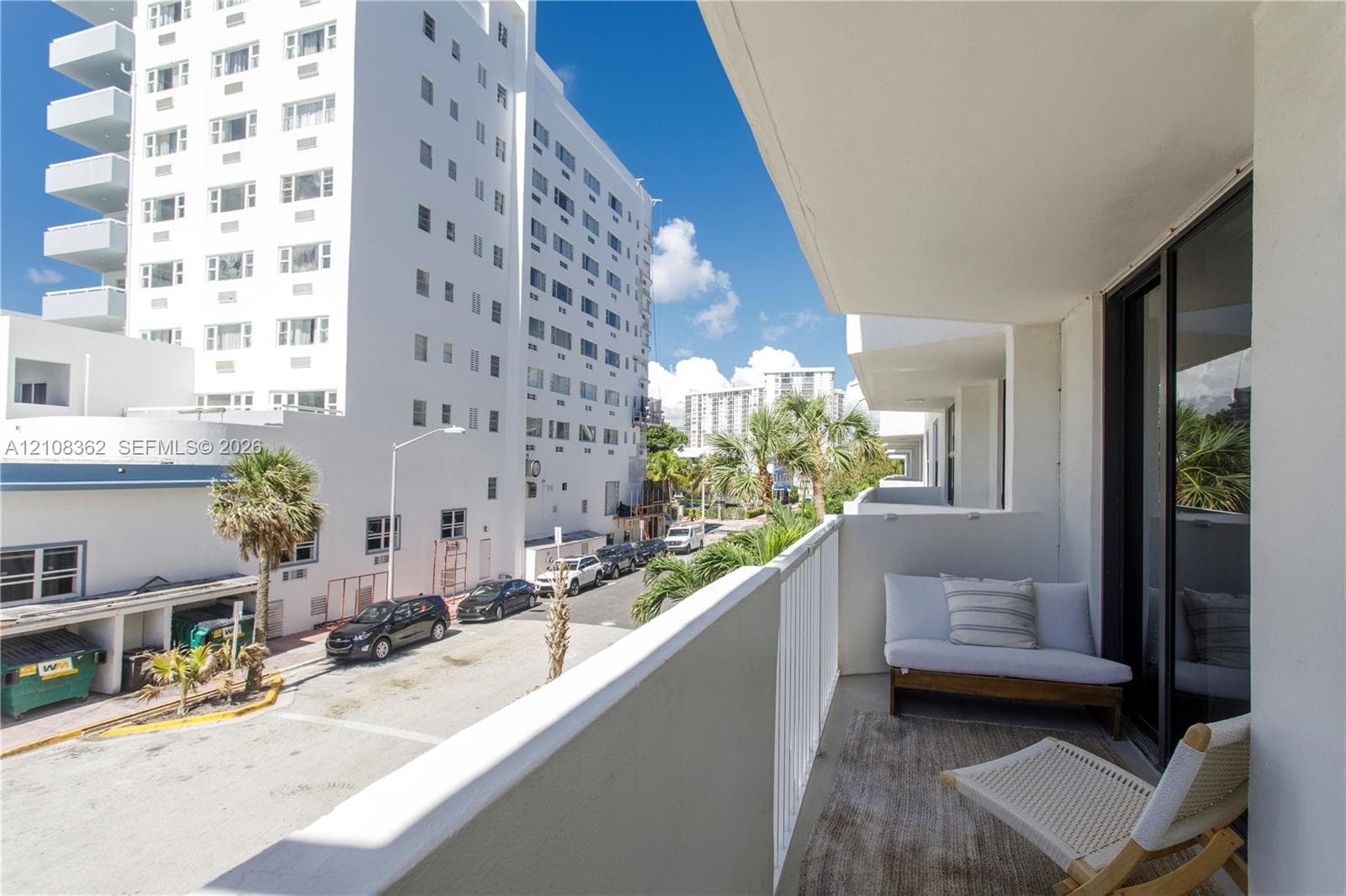 Private covered balcony featuring concrete flooring, a solid wall partition, and white metal railing