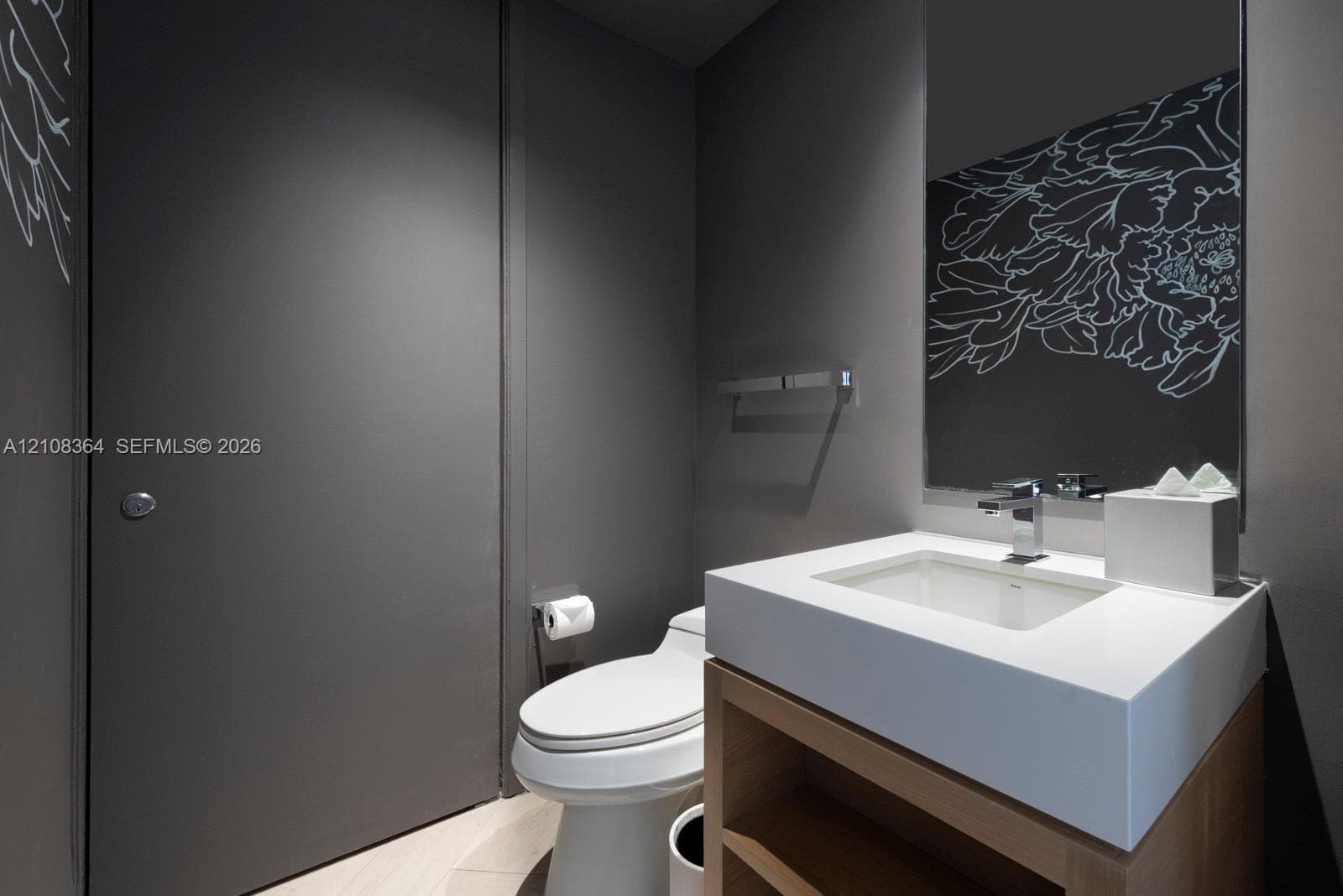 Modern vanity featuring an integrated rectangular sink and stone countertop, wood-finish open cabinetry, wall-mounted faucet, and a wall-to-wall mirror with decorative etching
