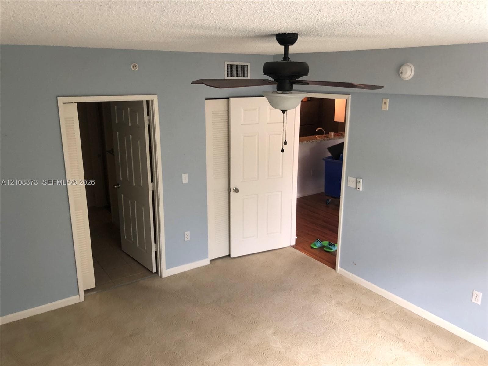 Neutral-toned wall-to-wall carpeting, ceiling-mounted paddle fan with integrated lighting, and multiple paneled interior doors