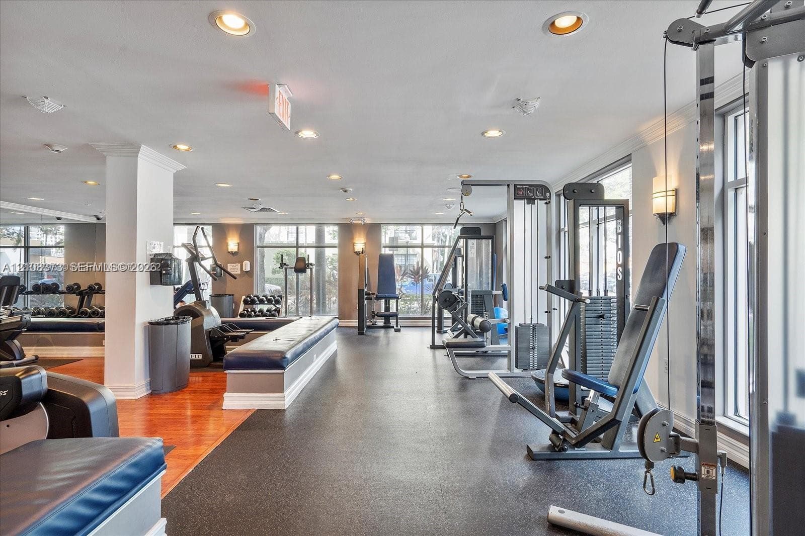 Fitness facility featuring expansive floor-to-ceiling windows, recessed lighting, and a combination of wood-finish and resilient rubber flooring