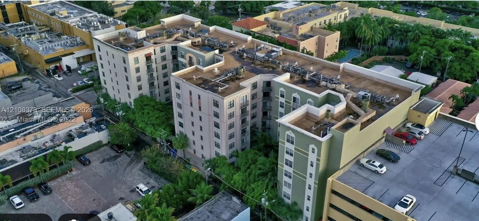 Multi-story complex featuring a structured exterior, arched window details, dedicated surface parking, and manicured perimeter landscaping