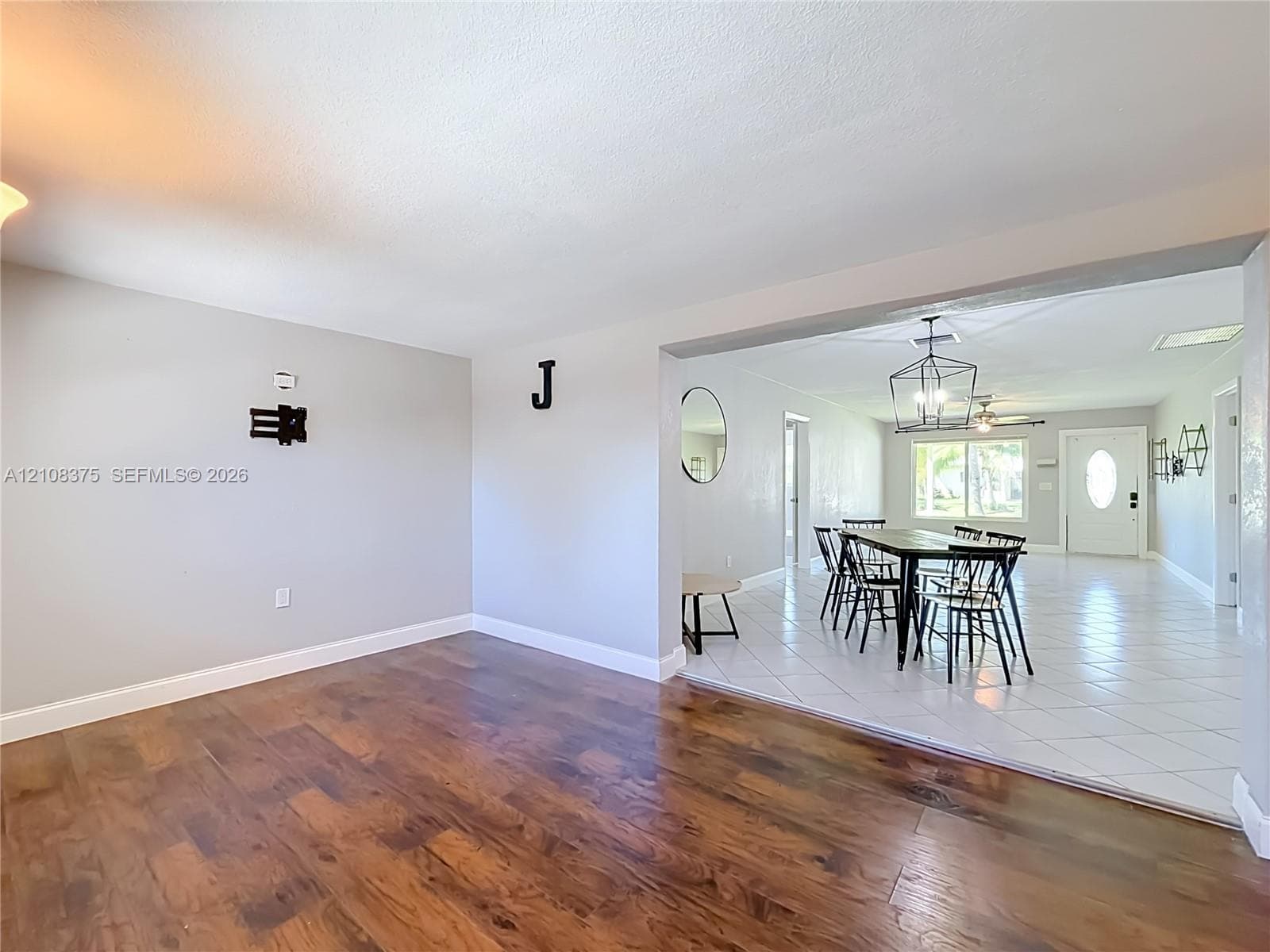 Wood-finish flooring, white ceramic tile flooring, geometric metal pendant lighting, and neutral wall tones